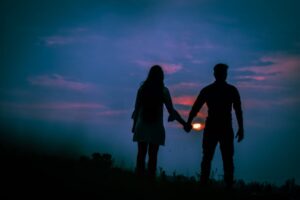 man and woman holding hands at sunset